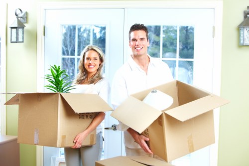Movers carrying furniture through a residential building in Bow